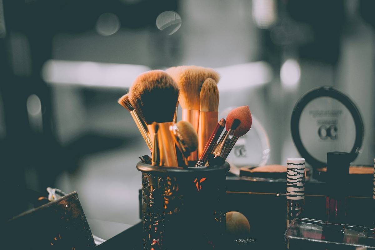 Infographic comparing makeup brushes, sponges, and fingers: absorption rates, bacterial retention, and finish types
