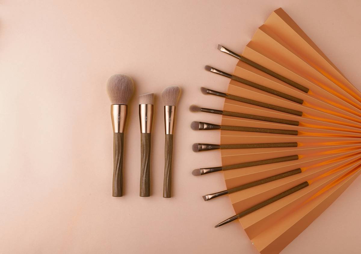 Side-by-side comparison of 4 makeup contour tools: angled synthetic brush, dual-ended sponge/tapered tip, dense stippling brush, and curved silicone blender showing product pickup and blend results on skin swatches.